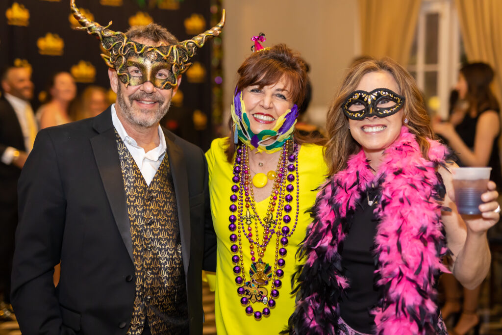 one man and two women wearing mardi gras masks and beads
