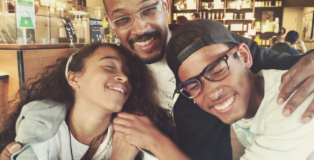 father hugs teenage son and daughter