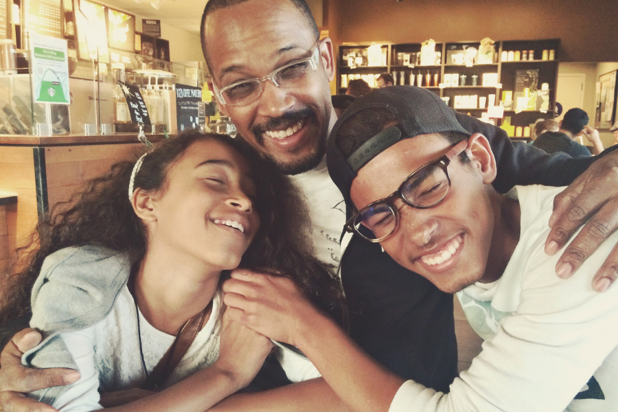 father hugs teenage son and daughter
