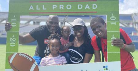 family stands on football field inside a large frame that says All Pro Dads