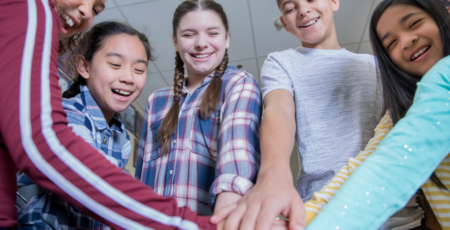 Group of students in a huddle with hands in the center