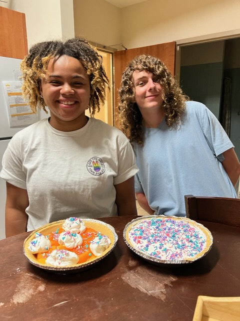 two teenagers smiling with desserts they made