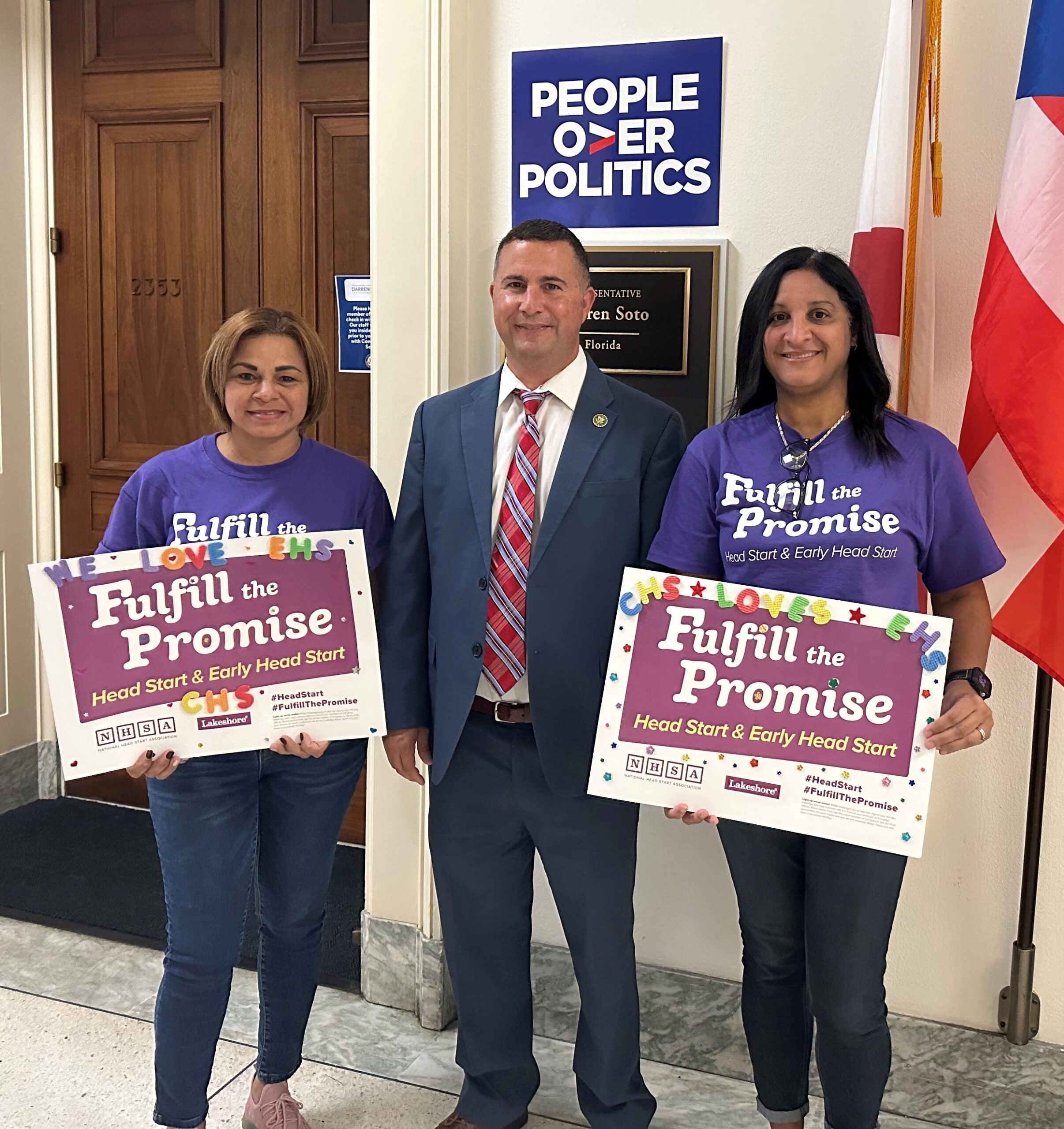 two women stand with a man in front of flags