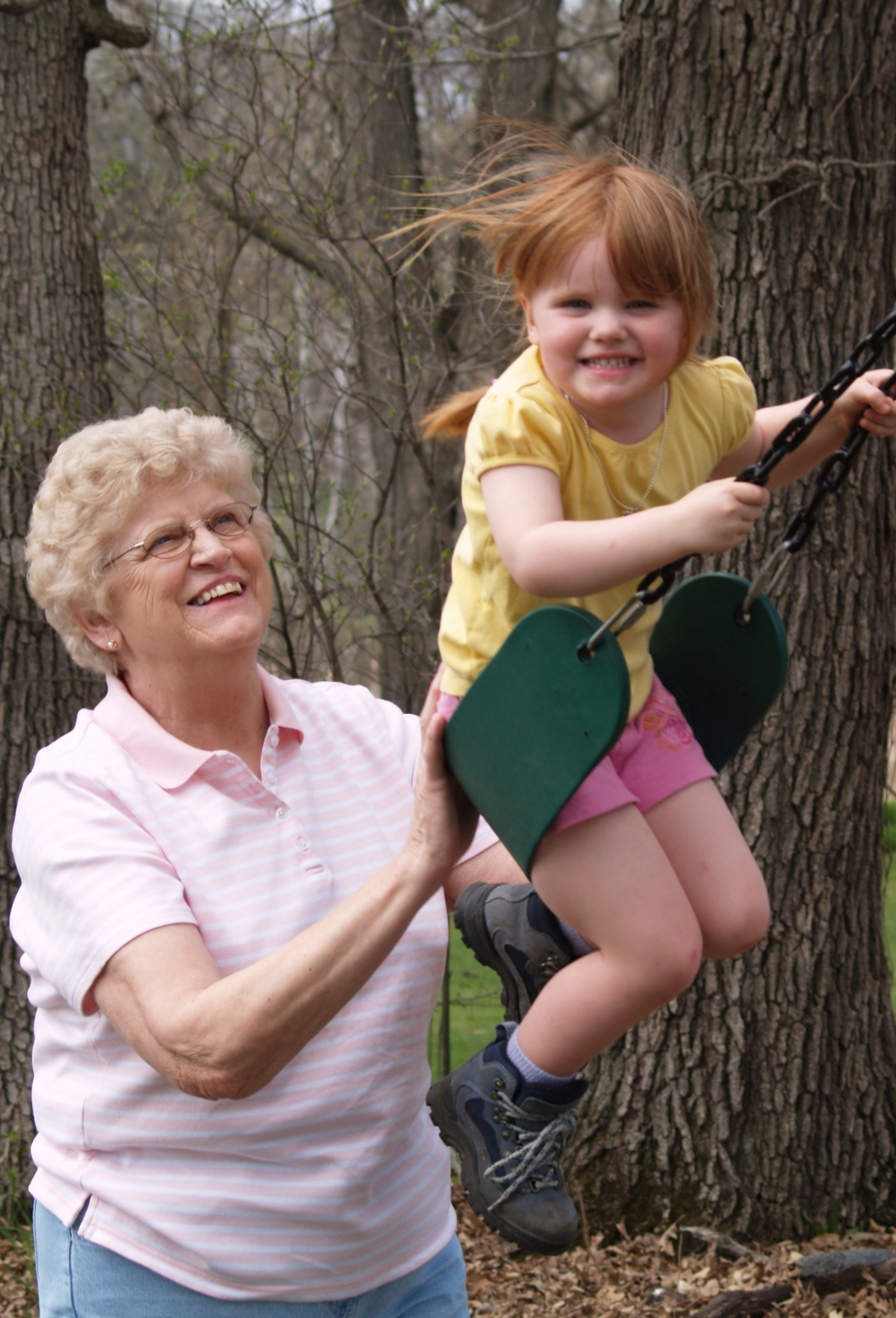 older woman pushing child on swing
