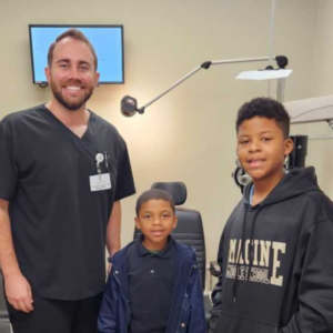 two young boys stand with a man in scrubs in a doctor's office
