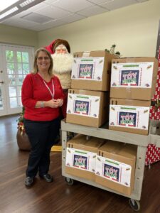 Women in red shirt stands next to packed boxes of toys