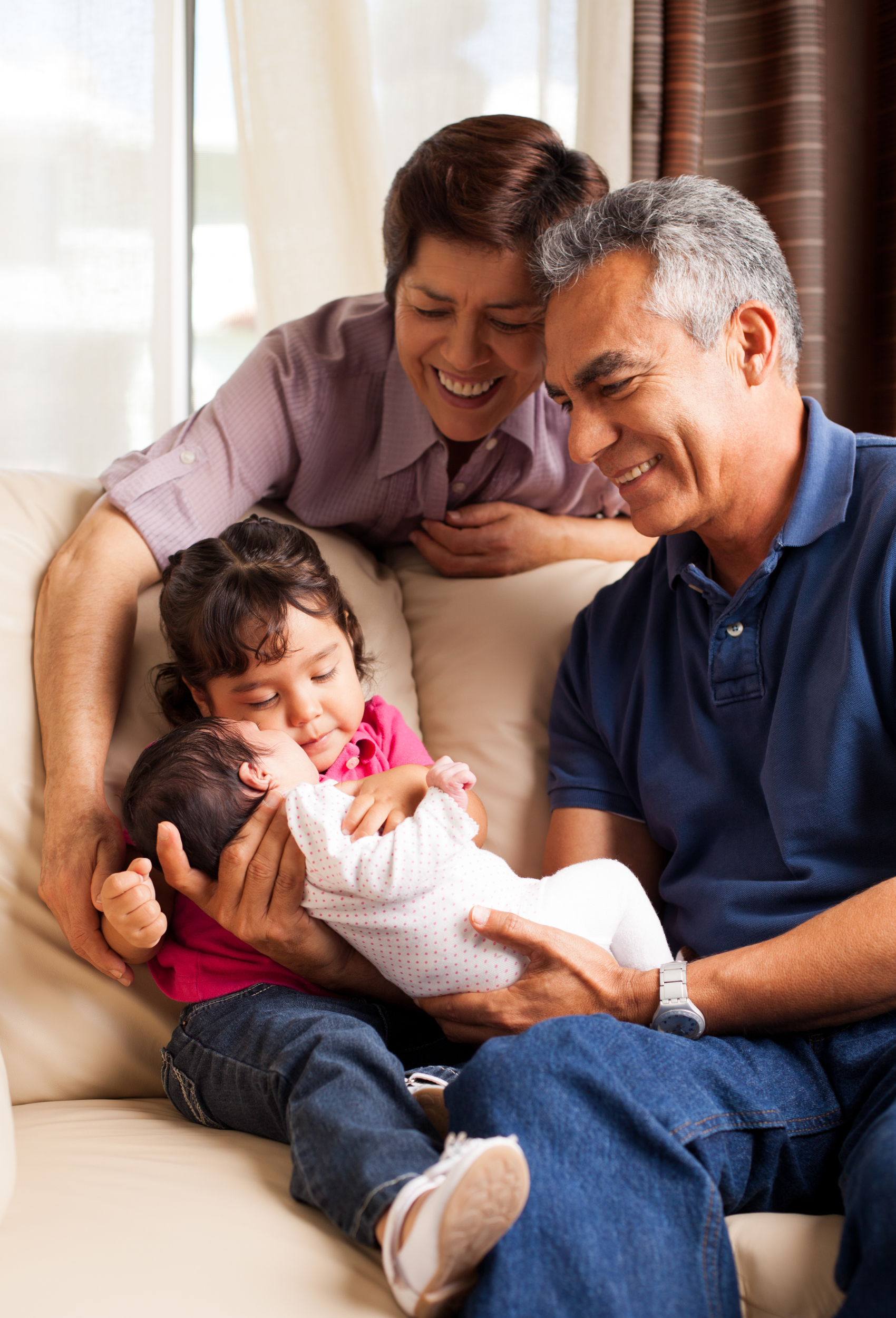 man and woman smiling down at a young child holding a baby