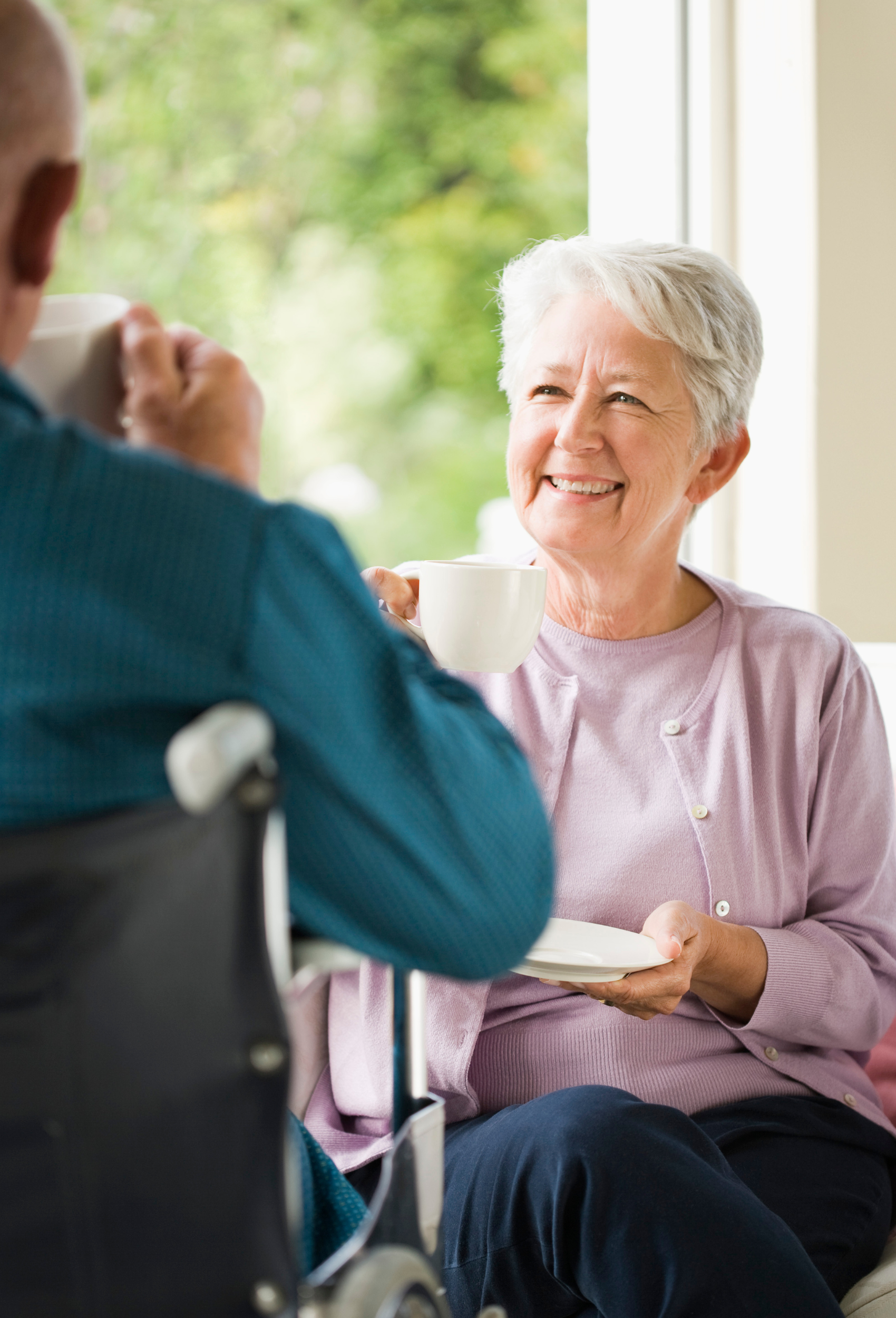 older woman drinking tea and talking to a companion