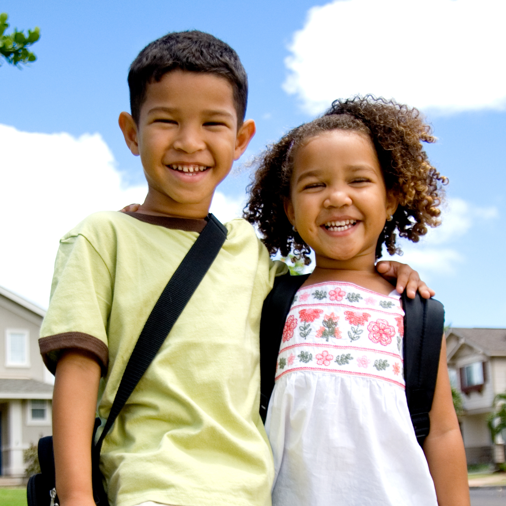 a boy and girl wearing backpacks smiling