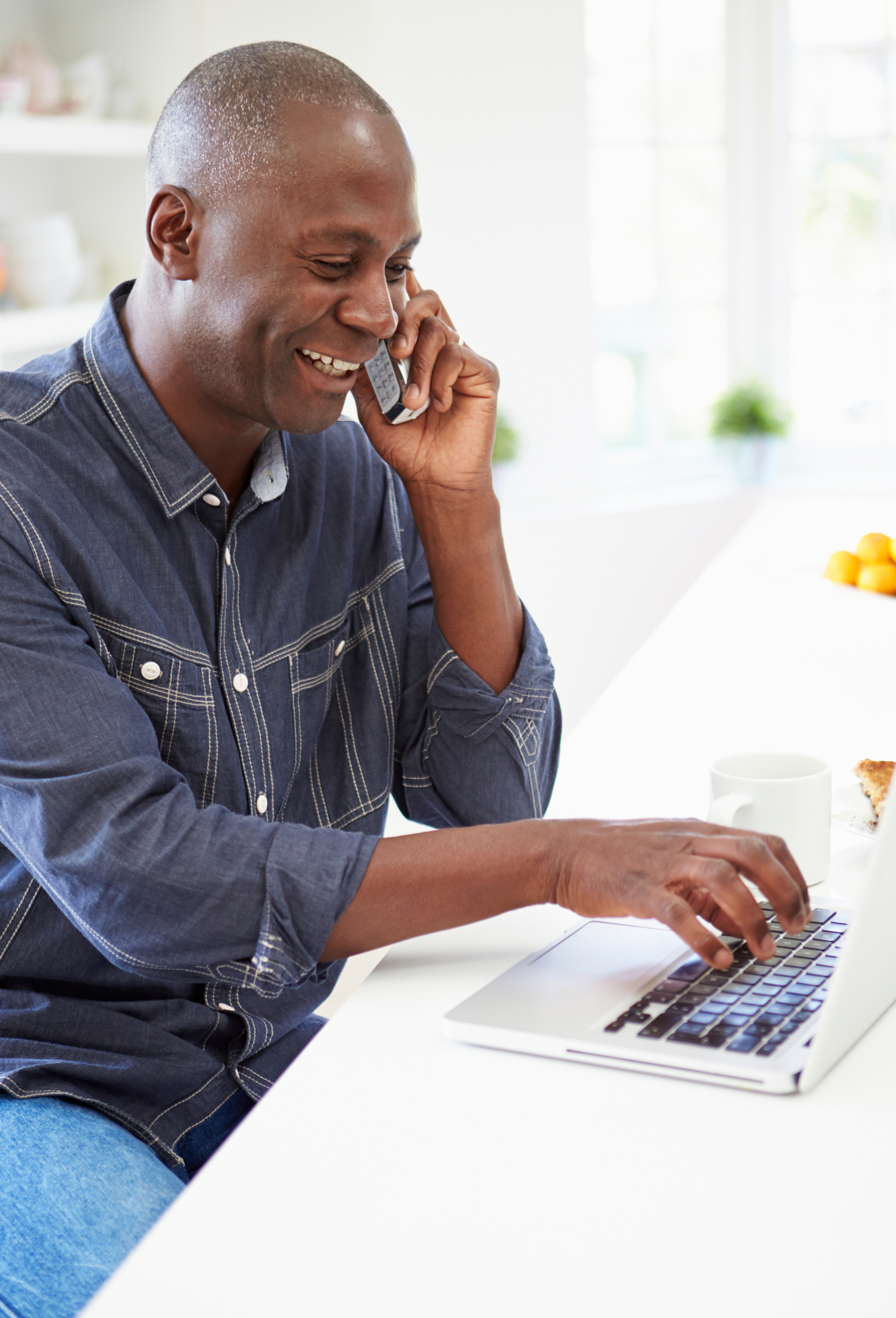 man talking on phone and working on laptop