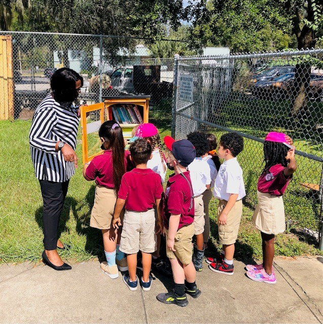 group of students gathered around little library