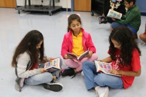 young girls sitting on the floor reading books