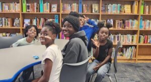 group of students sitting at a desk in the library